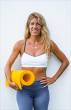 Fitness and yoga session with a young blonde Caucasian instructor dressed in a casual outfit. On a white background