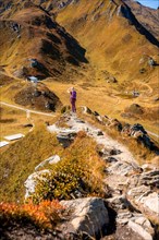 Wanders' woman on the way to the summit cross in rocky mountain landscape in autumn