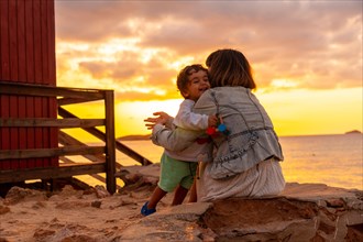 Mother hugging her son at sunset in Cala Comte beach on the island of Ibiza. Balearic