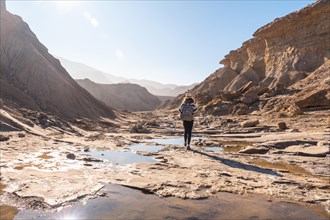 A young woman walking along the water in the desert on a trek on the Rambla Las Salinas in the desert of Tabernas