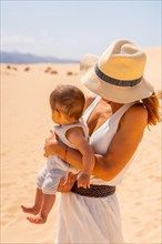 Pretty young mother with her son on vacation in the dunes of the Corralejo Natural Park