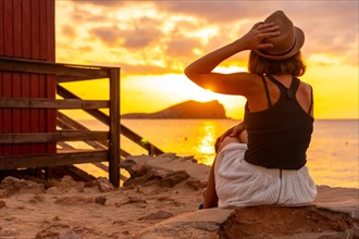 Woman with hat at sunset in Cala Comte beach on the island of Ibiza. Balearic