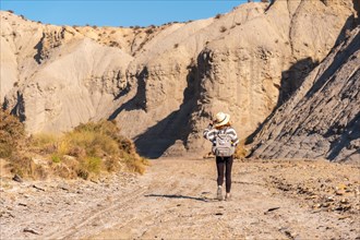 A young hiker with backpack and straw hat in the desert of Tabernas