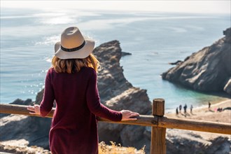 A young tourist girl with a hat looking at the beautiful Cala Penon cut off a virgin and hidden beach in Almeria. Mediterranean sea on the coast. Almanzora Caves