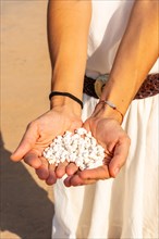 A young woman with stones in her hand on Popcorn Beach near the town of Corralejo