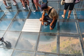 A tourist on the glass floor at the highest viewpoint called Cabo Girao in Funchal. Madeira