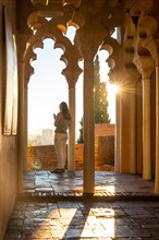 A tourist hunched over a column at sunset from the Arab doors of a courtyard of the Alcazaba in the city of Malaga