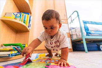 Young Caucasian mother playing with her in the room with toys. Baby less than a year learning the first lessons of her mother. Boy playing on the floor with toys