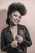 A closeup grayscale portrait of a funky stylish woman in a leather jacket posing indoors