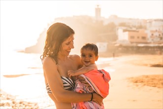 A young mother with her six-month-old baby enjoying a sunset on a beach