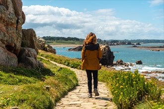 A young woman walking along the paths of the beautiful coastline at low tide of Le Gouffre de Plougrescant