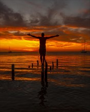 A young man in the water at the Orange Sunset on the West End beach of Roatan