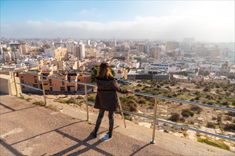 A young tourist girl looking at the city from the Cerro San Cristobal viewpoint in the city of Almeria