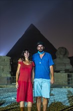 A tourist couple at the sound and light show at the beautiful pyramids and sphinx of Giza. Night in the city of Cairo. Africa