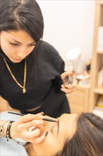 Vertical close-up photo of a professional makeup artist making up a client