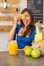 Sensual playful woman promoting a organic fresh made orange juice standing on the counter of a cafeteria