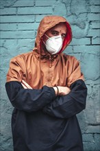 A young man in mask and hood leaning against a wall. First walks of the uncontrolled Covid-19 pandemic