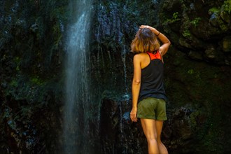 An unrecognizable young woman at the waterfall at the Levada do Caldeirao Verde