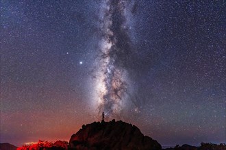 Silhouette of a young man under the stars looking at the lactea way of the Caldera de Taburiente near the Roque de los Muchahos on the island of La Palma