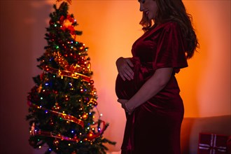 Silhouette of a beautiful pregnant woman decorating with the Christmas tree