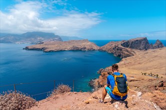 A young man looking at the landscape of Ponta de Sao Lourenco from the viewpoint in summer
