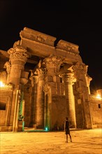 A young woman visiting at night the beautiful temple of Kom Ombo