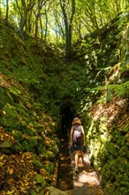 A young woman on her way to a cave on the trail at Levada do Caldeirao Verde