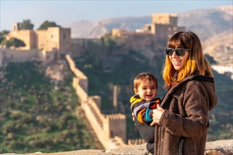 A young mother with her baby at the viewpoint of Cerro San Cristobal de la Muralla de Jairan and the Alcazaba in the town of Almeria