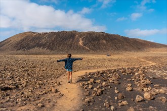 A young woman walking on the path to the Crater of the Calderon Hondo volcano near Corralejo