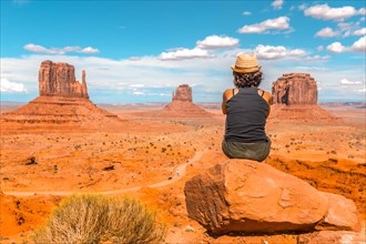 A young girl with black t-shirt sitting on a stone in the Monument Valley National Park in the visitor center. Utah