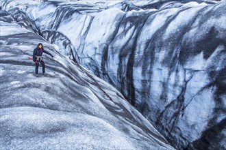 A young woman looking at one of the dangerous ice trekking holes in the Svinafellsjokull glacier. Iceland