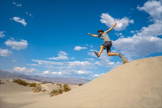A young man jumping in desert on a summer afternoon in Death Valley