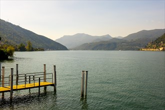 Jetty on the Waterfront in a Sunny Summer Day and with Lake Lugano and Mountain View over Morcote