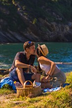 Romantic scene of a couple kissing on the picnic in the mountains by the sea enjoying the heat