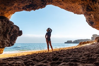 Silhouette of a woman in the cave on the beach in the Algarve