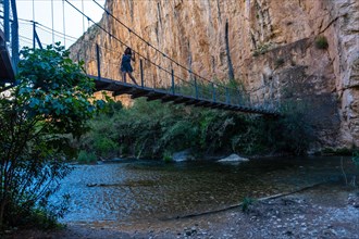 A young girl crossing the wooden suspension bridges. Ruta de los Pantaneros in the town of Chulilla in the Valencian community. Spain