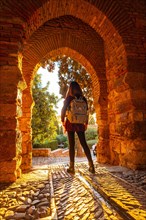 A tourist at sunset at the gate of the Alcazaba wall in the city of Malaga