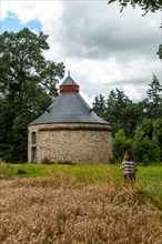 A young girl next to the thatched barn in French Brittany in the summer of July