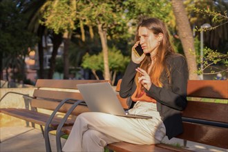 Horizontal photo with copy space of a casual businesswoman talking to the mobile while working sitting outdoors