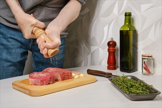 Hands of unrecognizable man seasoning beefsteak with salt
