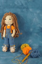 Amigurumi doll handmade on a blue background with the yarns used for its elaboration