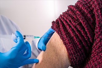 Female doctor injecting the coronavirus vaccine to an elderly lady. Antibodies