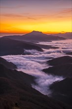 Fog between the mountains of the Basque country next to Mount Larrun at the golden hour of dawn. Vertical photo