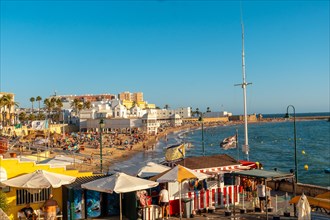 Bathers on the beach of La Caleta in the summer sunset of the city of Cadiz. Andalusia