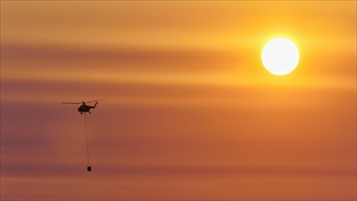 Firefighting helicopter in sunset