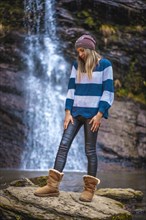 A thoughtful straight-haired blonde girl in a blue and white wool sweater in a waterfall. Lifestyle session