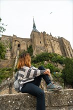 A young tourist visiting the famous Mont Saint-Michel Abbey in the Manche department