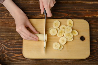 Top view of female hands cutting fresh banana with knife