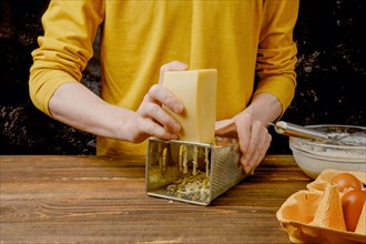 Close up of male hands grating cheese on kitchen table
