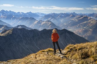 A woman stands on the Nebelhorn and looks into the camera